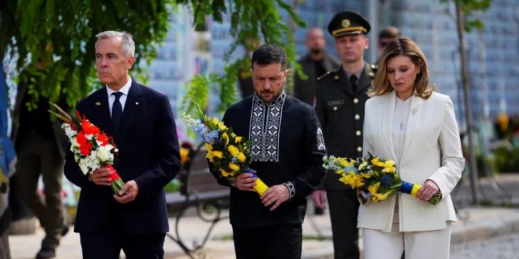 Canada's Prime Minister Mark Carney joins Ukrainian President Volodymyr Zelensky and his wife, Olena Zelenska, as they lay wreaths at the memorial wall in Kyiv
