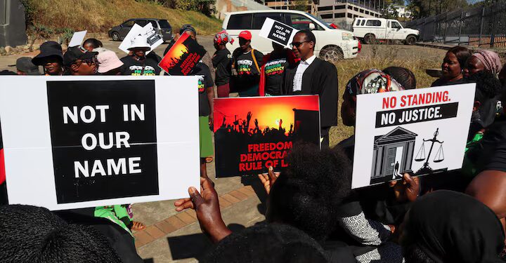 Protesters hold placards as lead applicant and lawyer Mzwandile Masuku addresses them outside the court, after a hearing was postponed, in Mbabane, Eswatini, August 22, 2025.