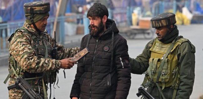 Indian paramilitary troopers frisk a pedestrian during a random search in Srinagar on November 11, 2025.