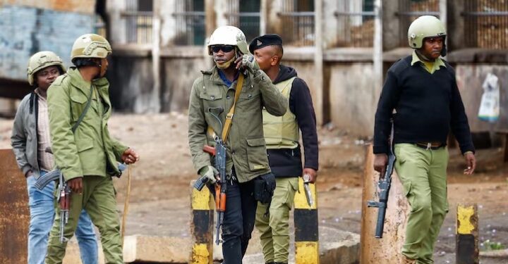 Tanzanian riot police officers walk, following a protest a day after a general election marred by violent demonstrations over the exclusion of two leading opposition candidates at the Namanga One-Post Border crossing point between Kenya and Tanzania, October 30, 2025