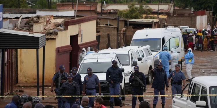South African police gather at the scene of a mass shooting where gunmen killed nine and injured at least 10 in a pub in Bekkersdal, South Africa, Sunday, Dec. 21, 2025.